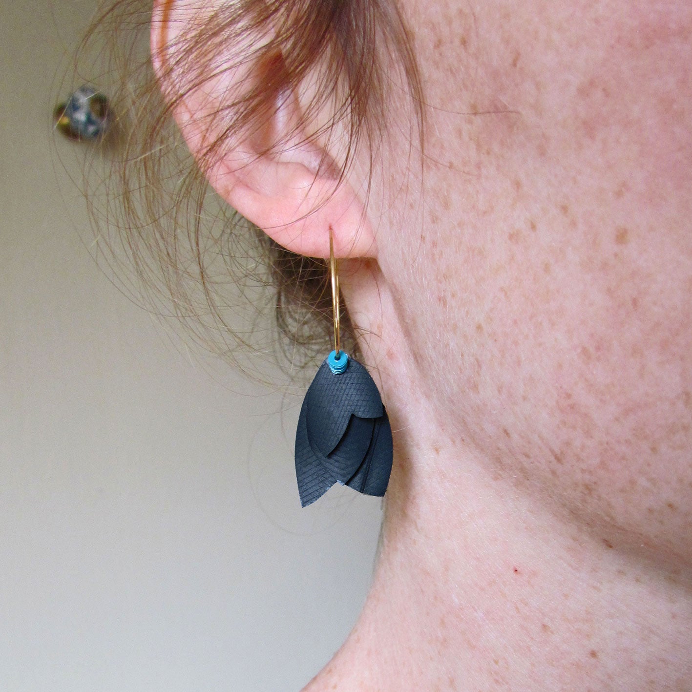 Boucles d'oreille créoles légères dorée aux pétales noires avec un soupçon de turquoise