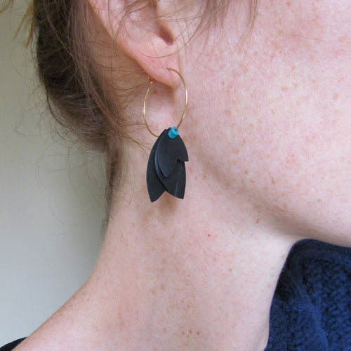 Boucles d'oreille créoles légères dorée aux pétales noires avec un soupçon de turquoise